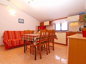 A compact kitchen with a dining area, a sofa, and a small table set for two.