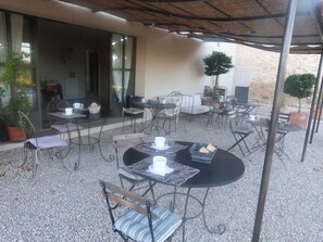 An outdoor patio area with round tables and chairs, a white sofa, and a potted plant. - La Bastide Saint Victor (Puyvert)