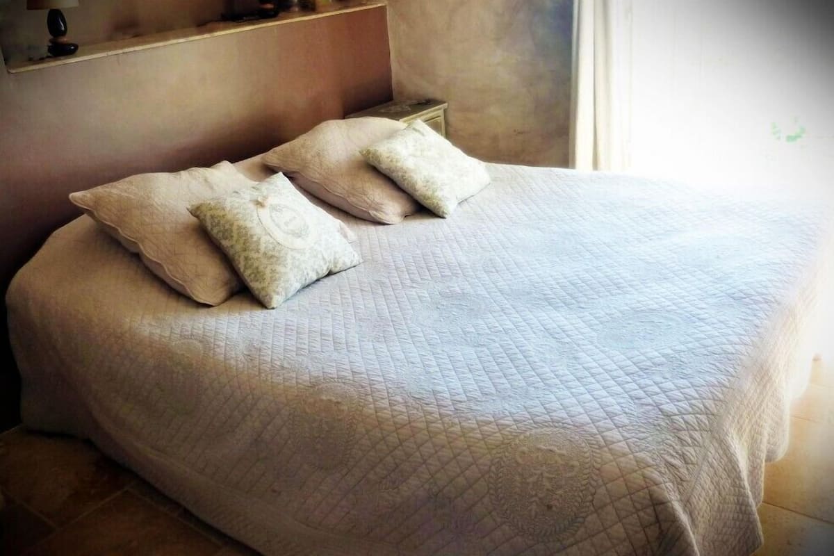 A neatly made bed with a quilted bedspread and two pillows.