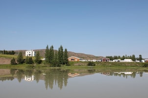 Una propiedad junto al lago con una casa blanca, un granero rojo y varias caravanas estacionadas cerca.