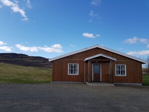 A wooden cabin with a front door, two windows, and a gravel driveway. - Skipalækur Guesthouse (Egilsstaðir)