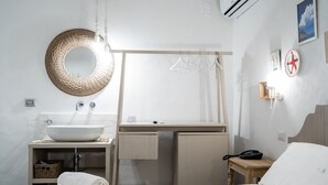 Un baño moderno con un espejo redondo grande, un lavabo blanco y una toalla en el suelo.