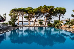 Una piscina al aire libre, sillones reclinables de piscina