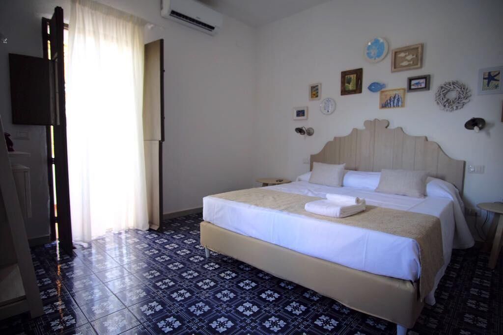 A hotel room with a bed, a television, and a window with curtains.