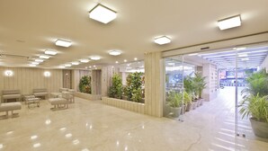 A spacious lobby with a polished marble floor, seating areas, and potted plants. - Scenaria Hotel (Ahmedabad)