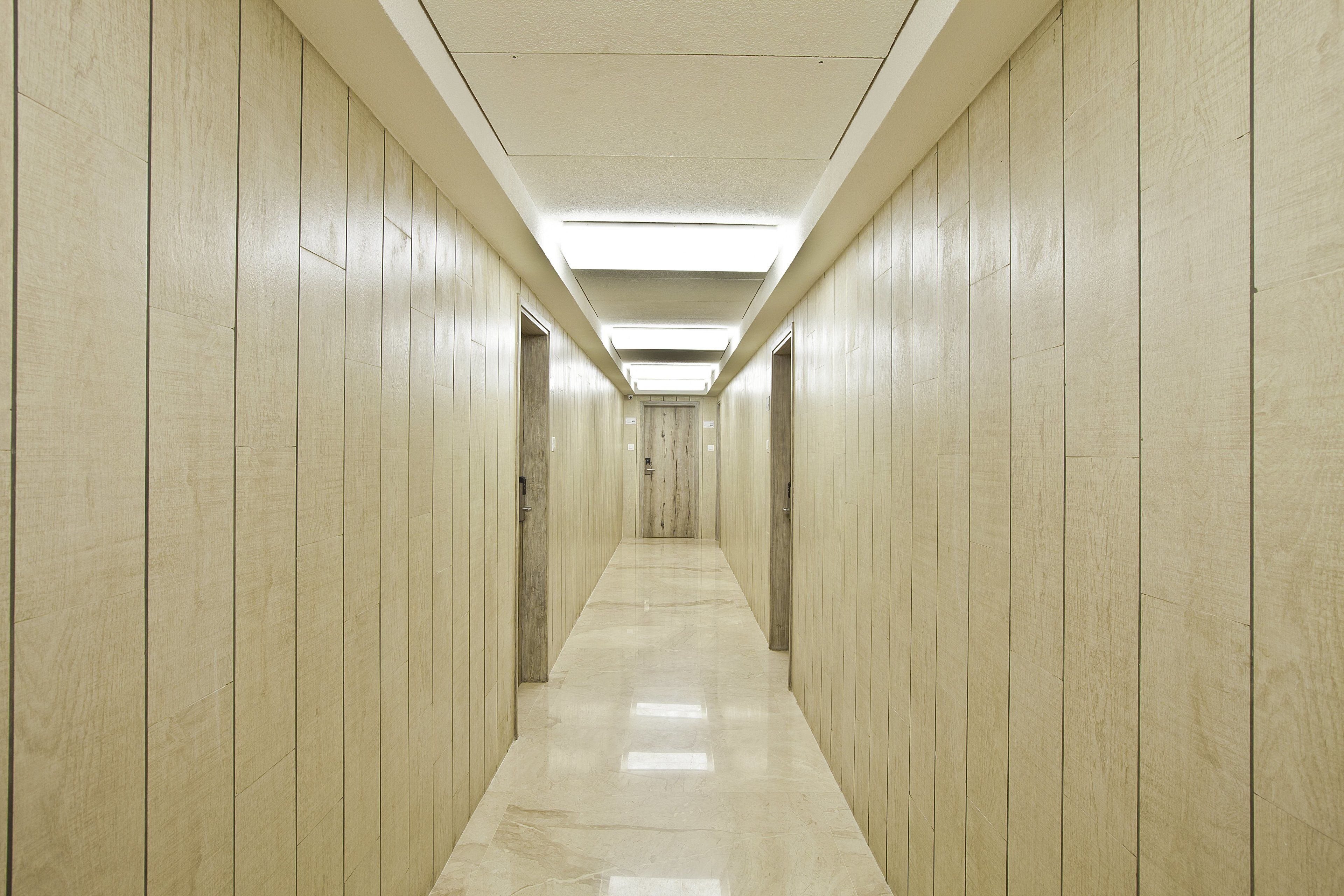 A long, narrow hallway with wooden paneling on the walls and a shiny, reflective floor.