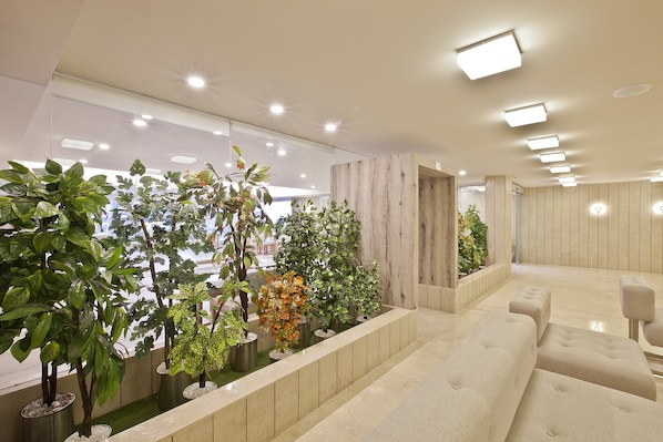 Un interior moderno con zona de estar, plantas en macetas y una pared de acento de madera.