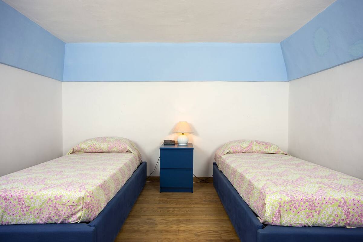 Ein kleines Schlafzimmer mit zwei Einzelbetten, einem Nachttisch mit Lampe und Holzboden.