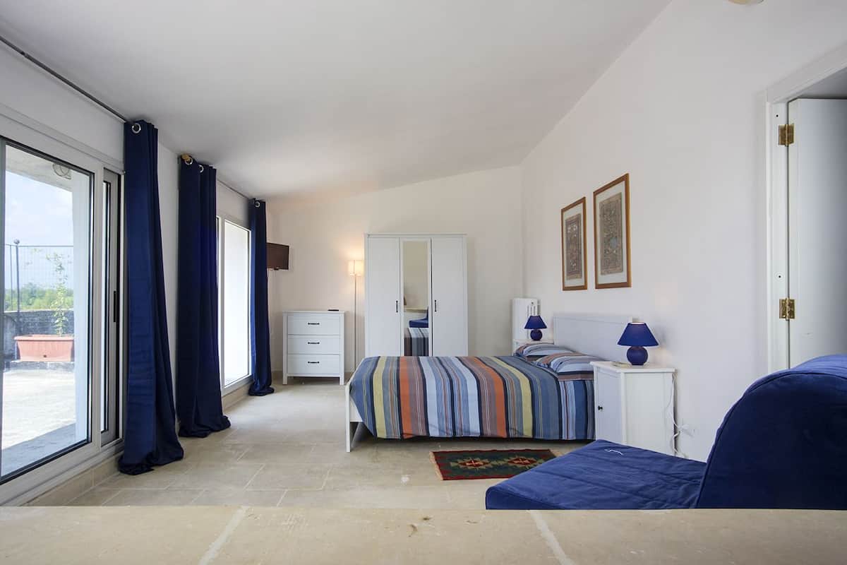 Ein Schlafzimmer mit Bett, Schminktisch, Nachttisch, Spiegel und einer Tür.