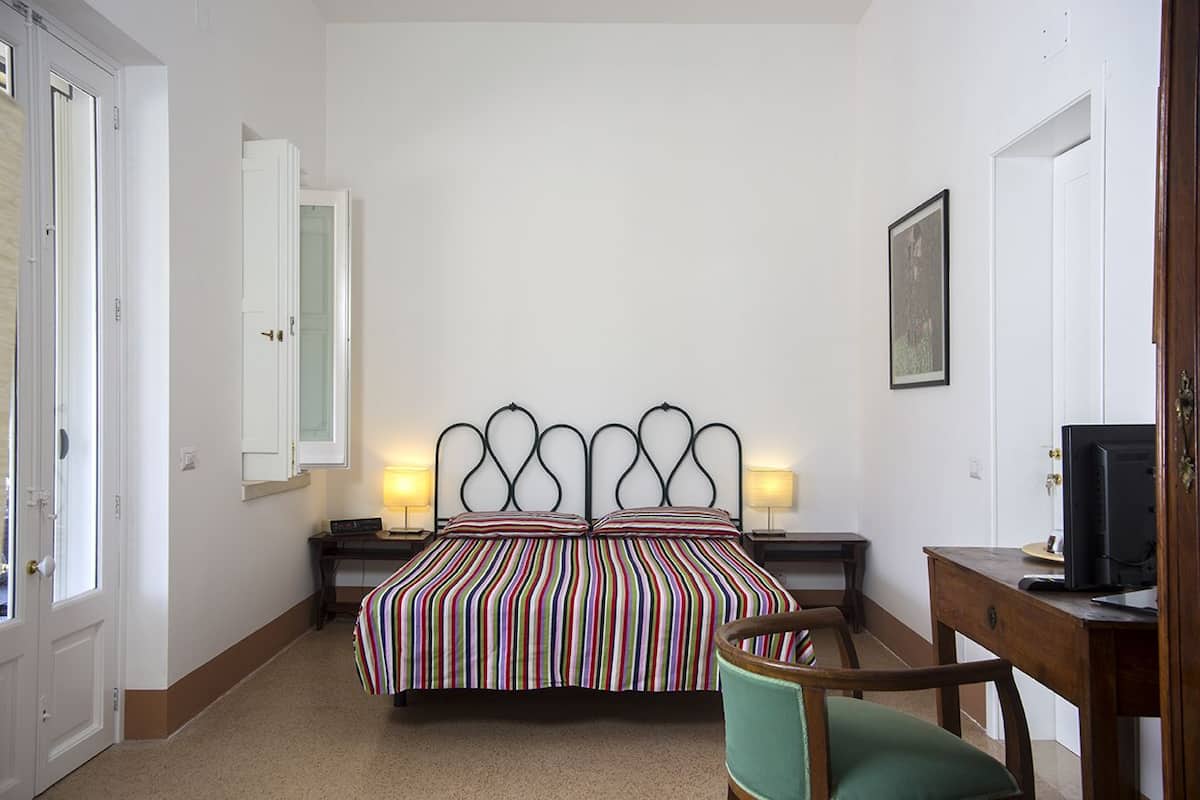 Ein Schlafzimmer mit einem Bett, Nachttischen, einem Schreibtisch und einem Stuhl.