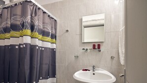 Ein Badezimmer mit Duschvorhang, Waschbecken, Spiegel und Ablage für Toilettenartikel.