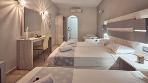 Ein modernes Hotelzimmer mit Schreibtisch, zwei Betten, einem großen Spiegel und einem durch einen Bogen sichtbaren Badezimmer.