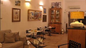 A dining area with a table set for two, surrounded by chairs. A cabinet with glass doors is visible in the background. - Hotel Villa Pimpina (Carloforte)