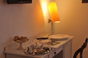 Ein Esstisch mit Lampe, einem Teller mit Essensresten, einer Fernbedienung und einer Tasse.