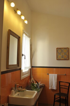 A bathroom with a sink, mirror, towel rack, and a decorative wall piece.