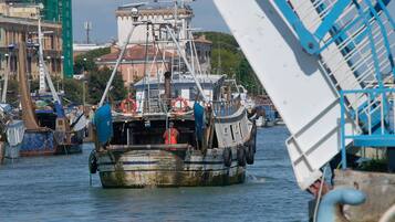 Ein großes, altes Fischerboot mit blau-weißer Farbgebung liegt im Hafen, im Hintergrund sind weitere Boote und Gebäude zu sehen.
