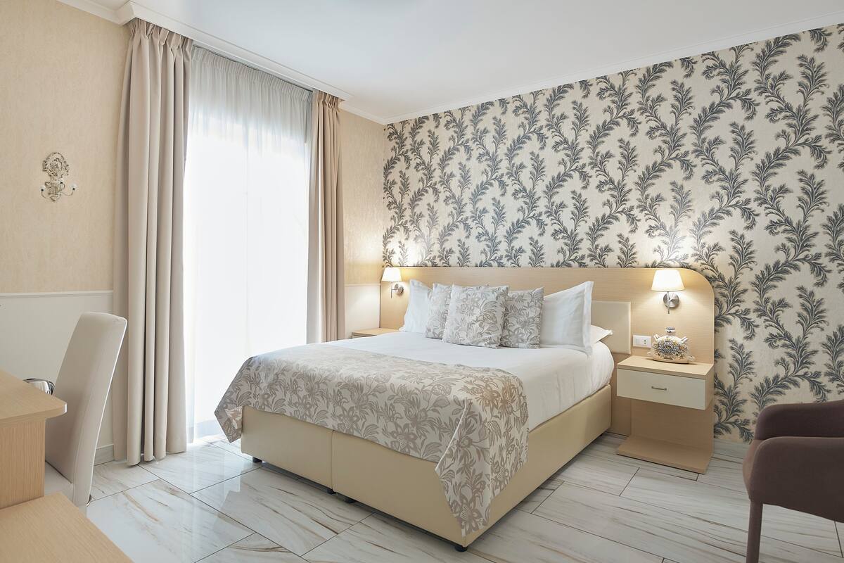 Una camera d'albergo con un letto, comodini, una sedia e una scrivania.