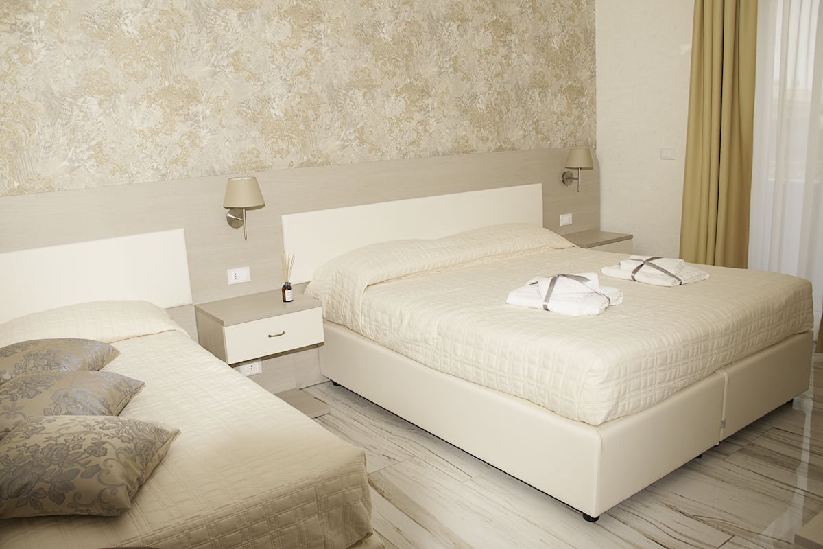 Una camera d'albergo con un letto grande, due comodini, una lampada e una decorazione a parete.
