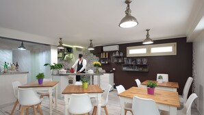 Une cuisine moderne avec des chaises blanches, des tables en bois et des luminaires suspendus.