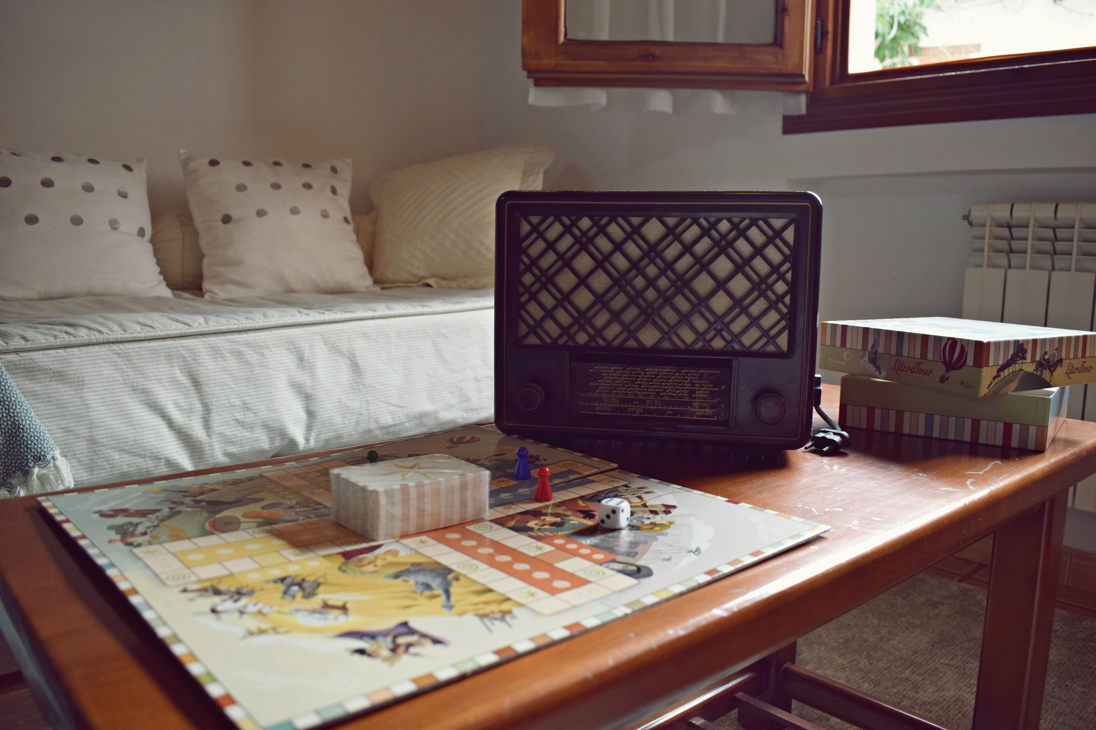 Un juego de mesa sobre una mesa de madera, con una cama y almohadas al fondo.