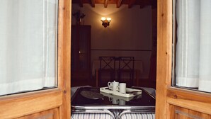 A room with a wooden ceiling, a wall-mounted light fixture, a bed with striped bedding, and a tray with a cup and saucer on a table. - Apartamentos Turísticos La Vida De Antes (Consuegra)