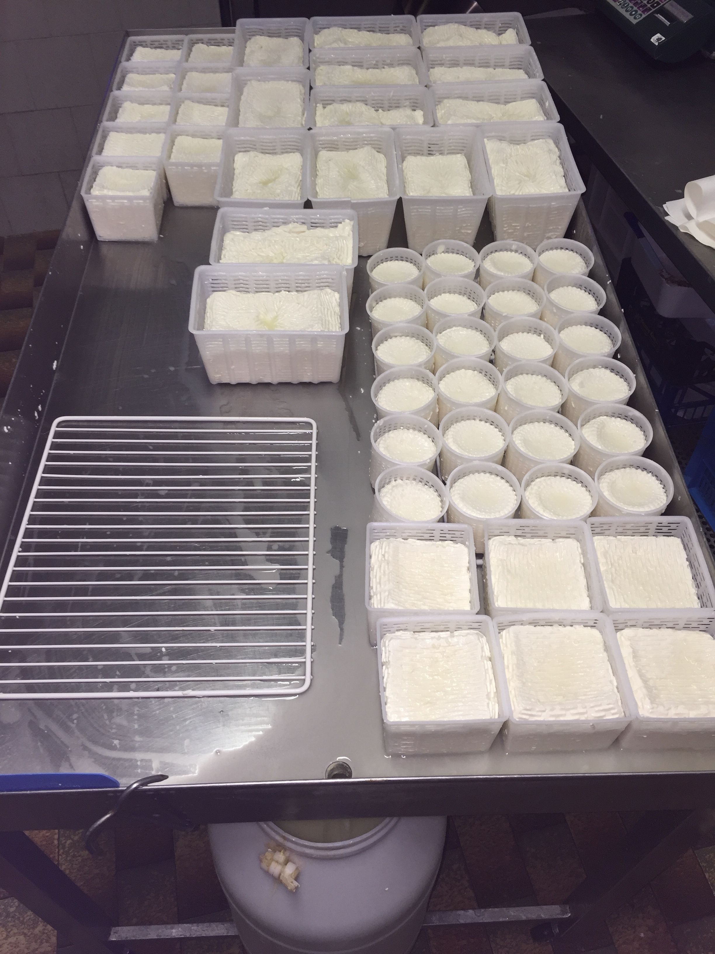 A stainless steel table with multiple plastic containers filled with white granular material, likely for food preparation.