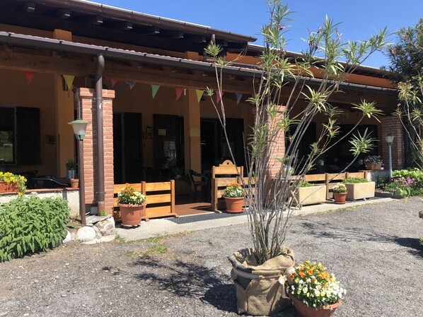 Um edifício com varanda coberta, plantas em vasos e área de estar ao ar livre.