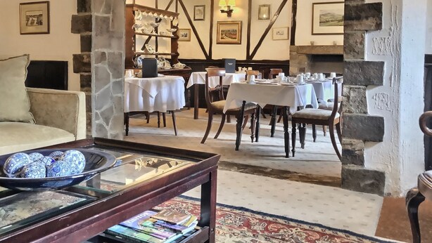 A dining area with tables set for meals, a fireplace, and stone walls. - Grove House (Leyburn)