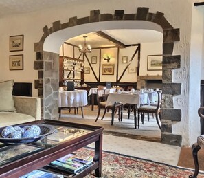 A dining area with tables set for meals, a fireplace, and stone walls. - Grove House (Leyburn)