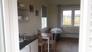 Una cocina pequeña con un lavabo, una mesa y sillas. Se ve una ventana con vistas al exterior.