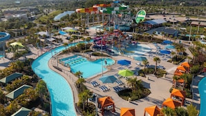 A water park with multiple slides and a swimming pool surrounded by lounge areas and umbrellas.