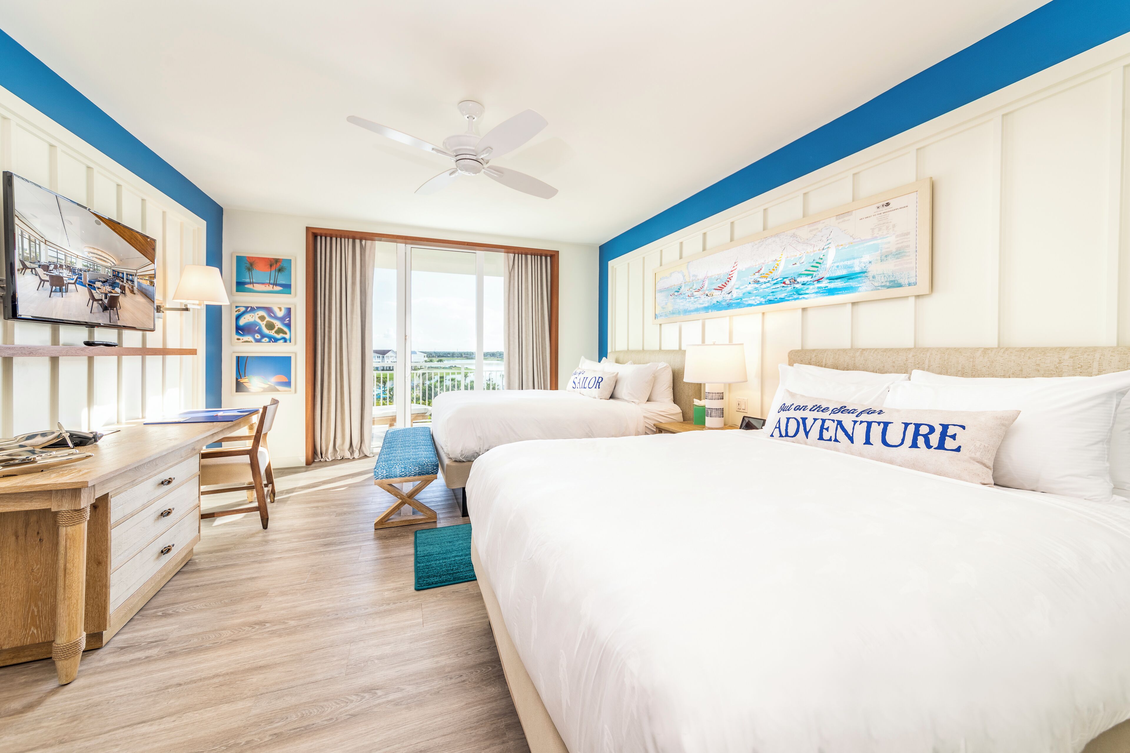 A hotel room with two beds, a desk, and a chair.