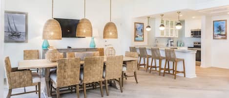 Uma cozinha moderna com armários brancos, uma ilha central e luminárias pendentes.