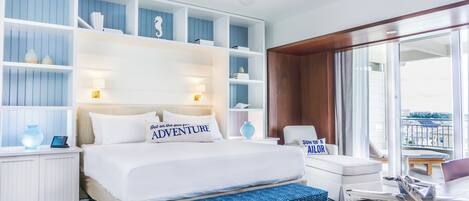 A modern hotel room with a large bed, a desk, and a balcony with a view.