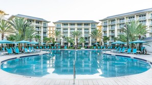 A pool area with lounge chairs and umbrellas, surrounded by multi-story buildings with balconies.