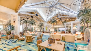 A spacious lobby with high ceilings, exposed beams, and a tropical theme featuring palm trees and hanging lights. - Margaritaville Resort Orlando with H2O Waterpark (Kissimmee)