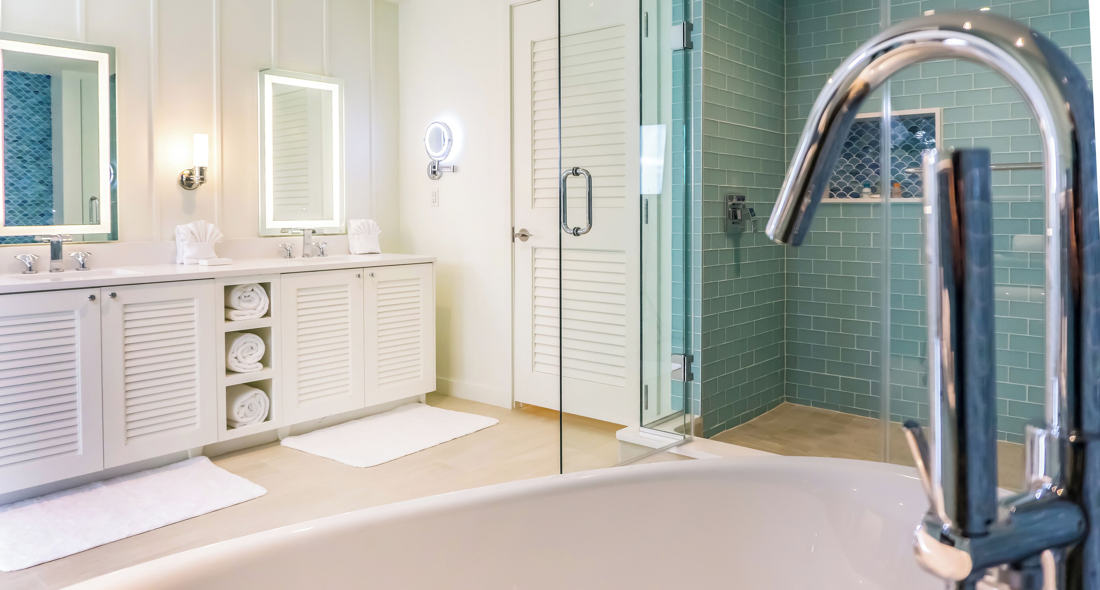Ein modernes Badezimmer mit einer Badewanne, zwei Waschbecken und einer Duschkabine aus Glas.