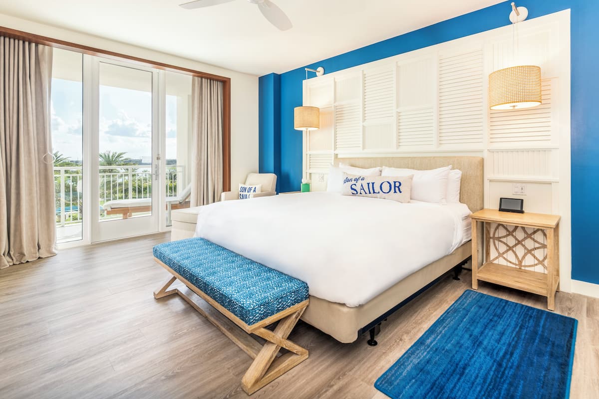 Ein Schlafzimmer mit einem großen Bett, einer Bank, einem Nachttisch und Blick ins Freie.