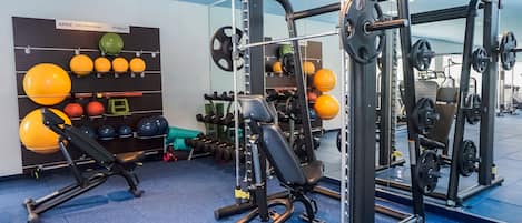 Un gimnasio con equipo de levantamiento de pesas, pelotas de ejercicio y mancuernas.