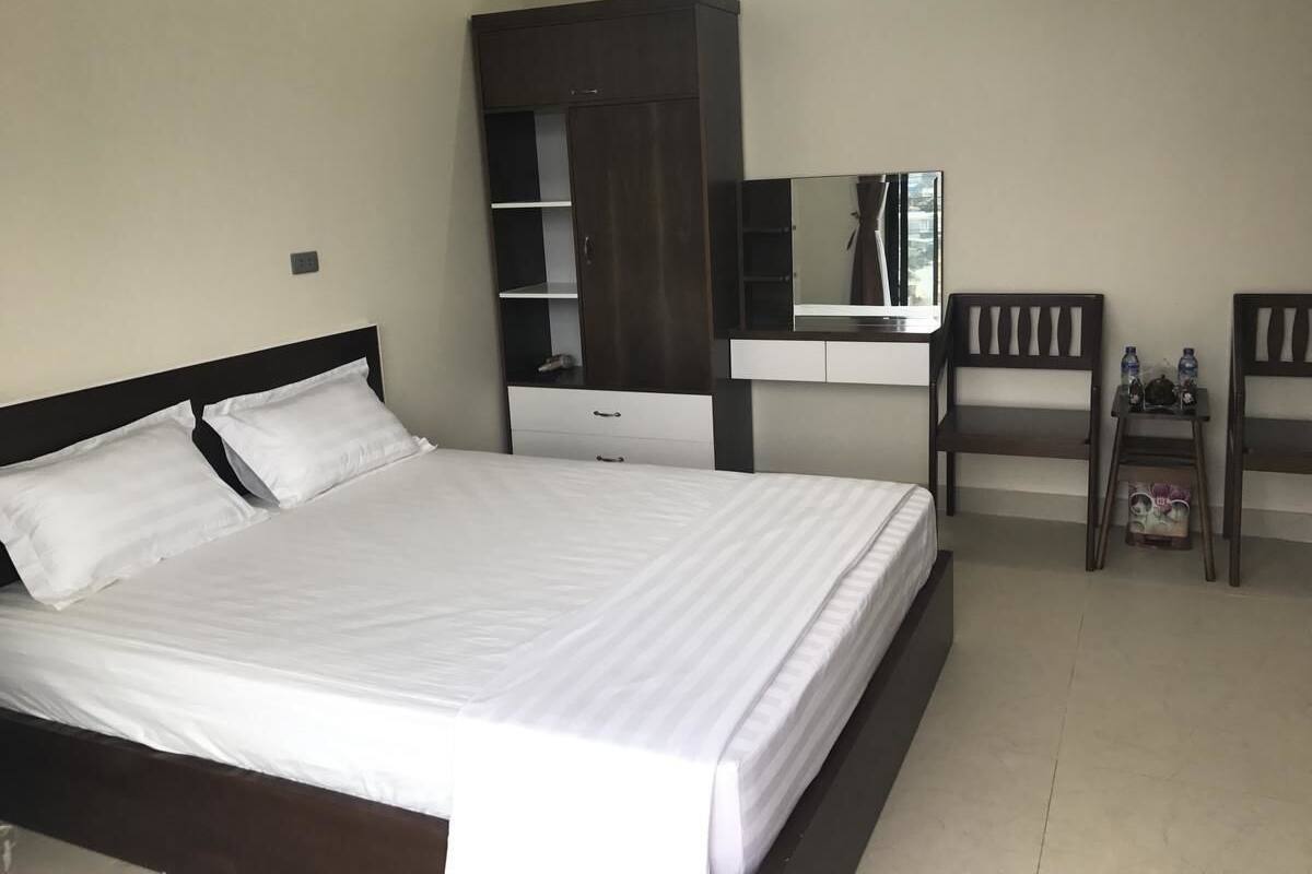 A bedroom with a bed, a wardrobe, a desk, and a chair.