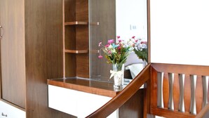 A wooden vanity with a mirror, a small vase with flowers, and a wooden chair. - Ben's Hotel (Thao Nguyen)