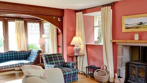 A cozy living room with a sofa, armchair, and a fireplace. - Finzean Estate Holiday Cottages (Banchory)