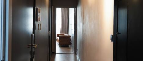 A hallway with a wooden floor, a sofa, and a door on the left.