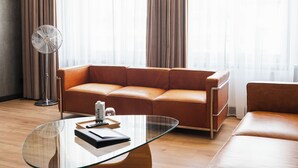 Una sala de estar moderna con un sofá de cuero, una mesa de centro de vidrio y un ventilador de pie.