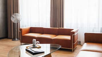 Una sala de estar moderna con un sofá de cuero, una mesa de centro de vidrio y un ventilador de pie.