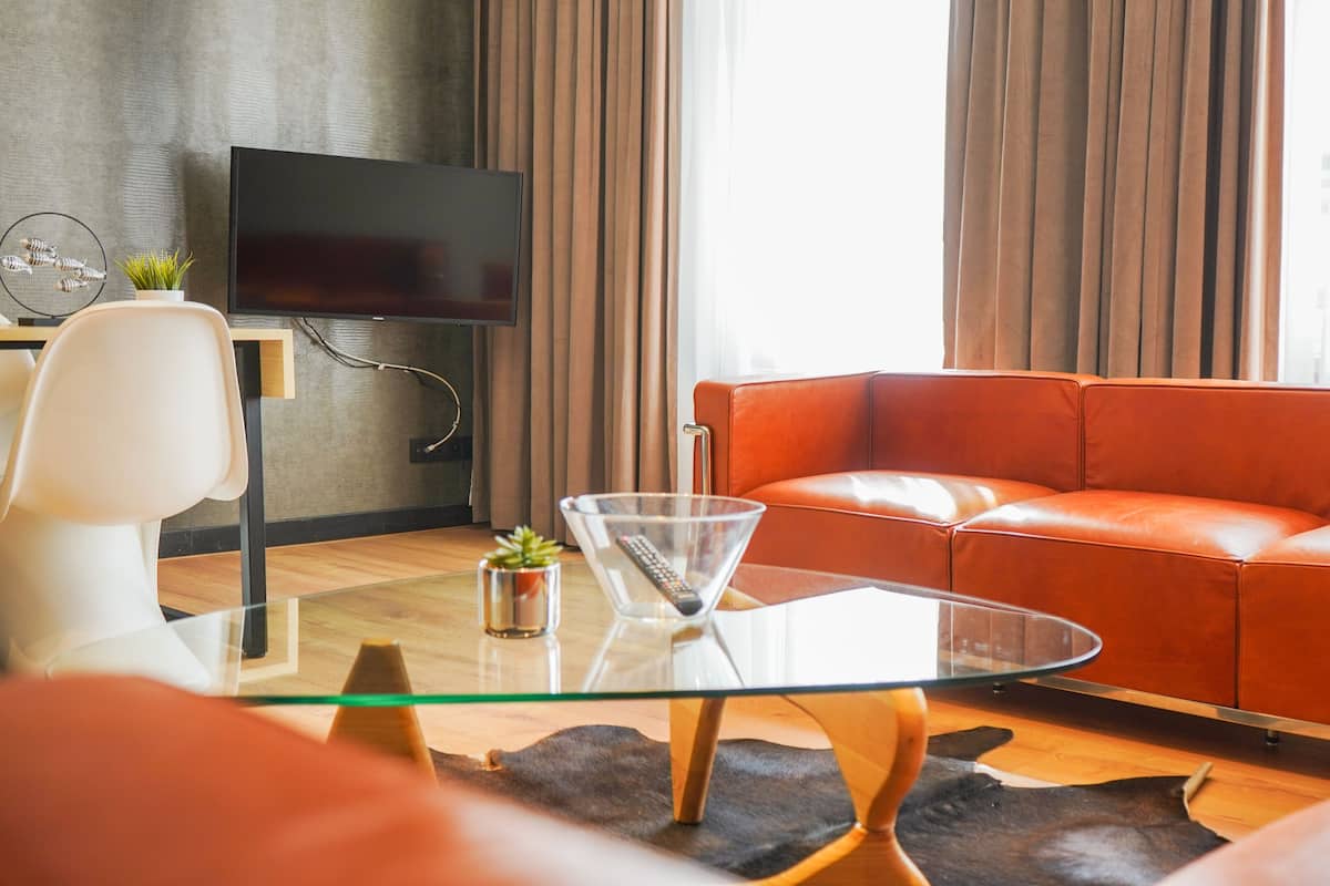 Un salon moderne avec un canapé en cuir, une table basse en verre et un téléviseur à écran plat fixé au mur.