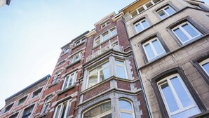 Un edificio de varios pisos con fachadas de ladrillo y piedra, ventanas amplias y detalles arquitectónicos ornamentados.