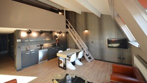 Una cocina moderna con comedor, una escalera y un televisor montado en la pared.