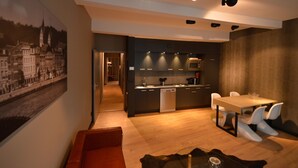Una cocina moderna con electrodomésticos integrados, un comedor con mesa de vidrio y una sala de estar con sofá rojo.