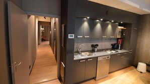 Una cocina moderna con muebles oscuros, un lavaplatos de acero inoxidable y un horno empotrado.